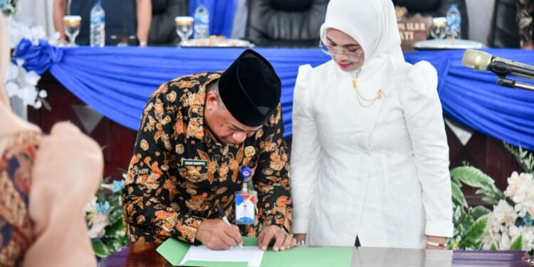 Bupati Boltim, Oskar Manoppo saat menandatangani berita acara pelantikan yang disaksikan langsung Ketua Dekranasda Boltim, Rosita Manoppo-Pobela