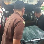 Petugas Kejati Sulut terlihat mengangkat koper hitam yang dijadikan barang bukti saat penggerebekan di sebuah toko emas di Kotamobagu, Senin (2/3/2026).