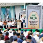 Gubernur Sulawesi Utara, Mayjen TNI (Purn) Yulius Selvanus (YSK), saat memberikan sambutan khusus di hadapan ribuan jamaah Sholat Idul Fitri 1447 Hijriah di Lapangan Tikala, Manado, Sabtu (21/03/2026). Dalam pesannya, Gubernur menekankan pentingnya menjaga persatuan dan menjadikan spirit Idul Fitri sebagai pondasi pembangunan daerah yang rukun dan maju. Di belakangnya tampak backdrop panggung yang memuat informasi detil mengenai pelaksanaan sholat, termasuk nama Khatib dan Imam. Di area panggung samping juga terlihat Gubernur yang didampingi pejabat Pemkot Manado.Foto: Diskominfo Pemprov Sulut.