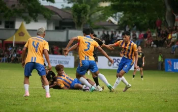 Aksi pemain Persibom saat berebut bola dengan tim lawan dalam laga Liga 4 Sulut. Pertandingan berlangsung sengit di lapangan hijau dengan dukungan penonton dari pinggir lapangan. Spanduk bertuliskan “Say No to Racism” turut menghiasi arena, menegaskan semangat sportivitas dan persatuan di tengah rivalitas kompetisi.