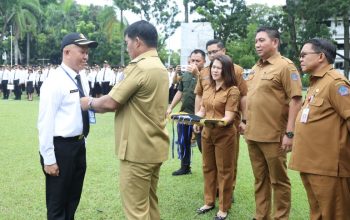 Gubernur Yulius Selvanus menyerahkan tanda orientasi kepada peserta PPPK dalam apel besar di halaman Kantor Gubernur Sulut, Selasa (28/4/2026). (Dokumentasi Humas Pemprov Sulut)