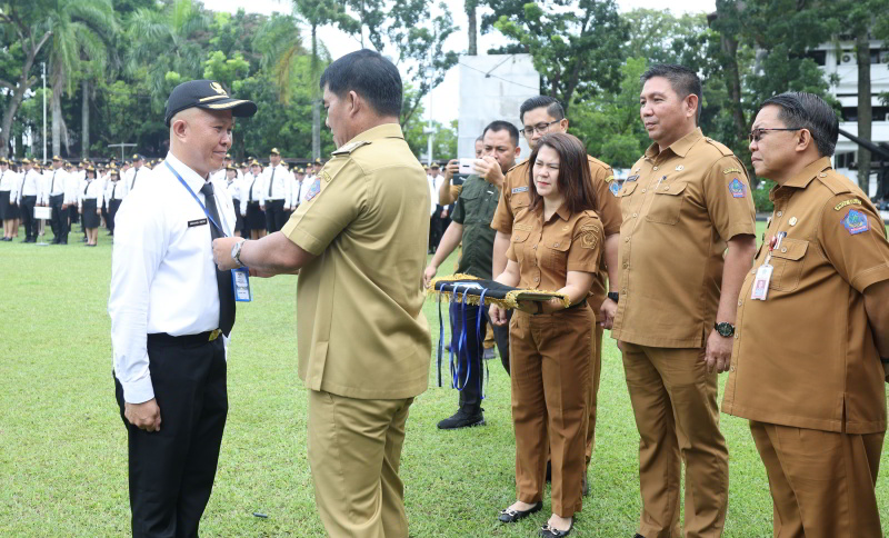 Gubernur Yulius Selvanus menyerahkan tanda orientasi kepada peserta PPPK dalam apel besar di halaman Kantor Gubernur Sulut, Selasa (28/4/2026). (Dokumentasi Humas Pemprov Sulut)