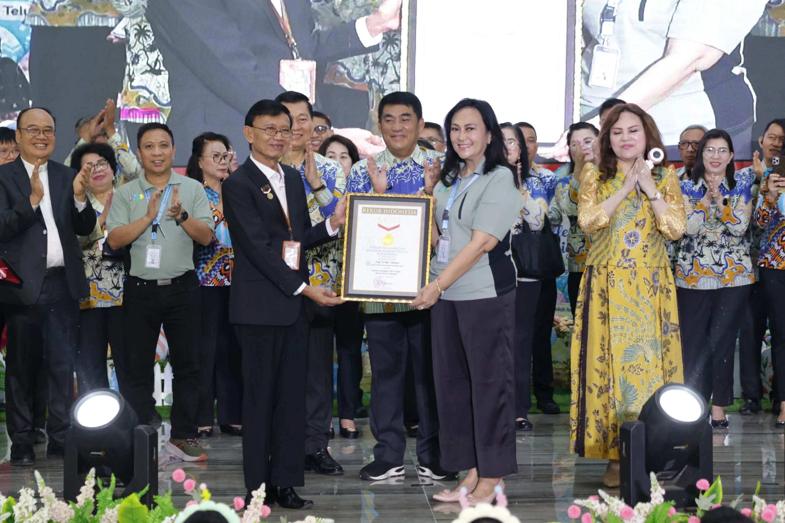 Ny. Anik Yulius Selvanus, Ketua TP-PKK Sulut sekaligus Ketua Panitia ‘Little Hands Big Joy’, menerima sertifikat rekor dunia MURI atas keberhasilan 2.000 anak menghias telur Paskah massal di Aula Mapalus, Manado.