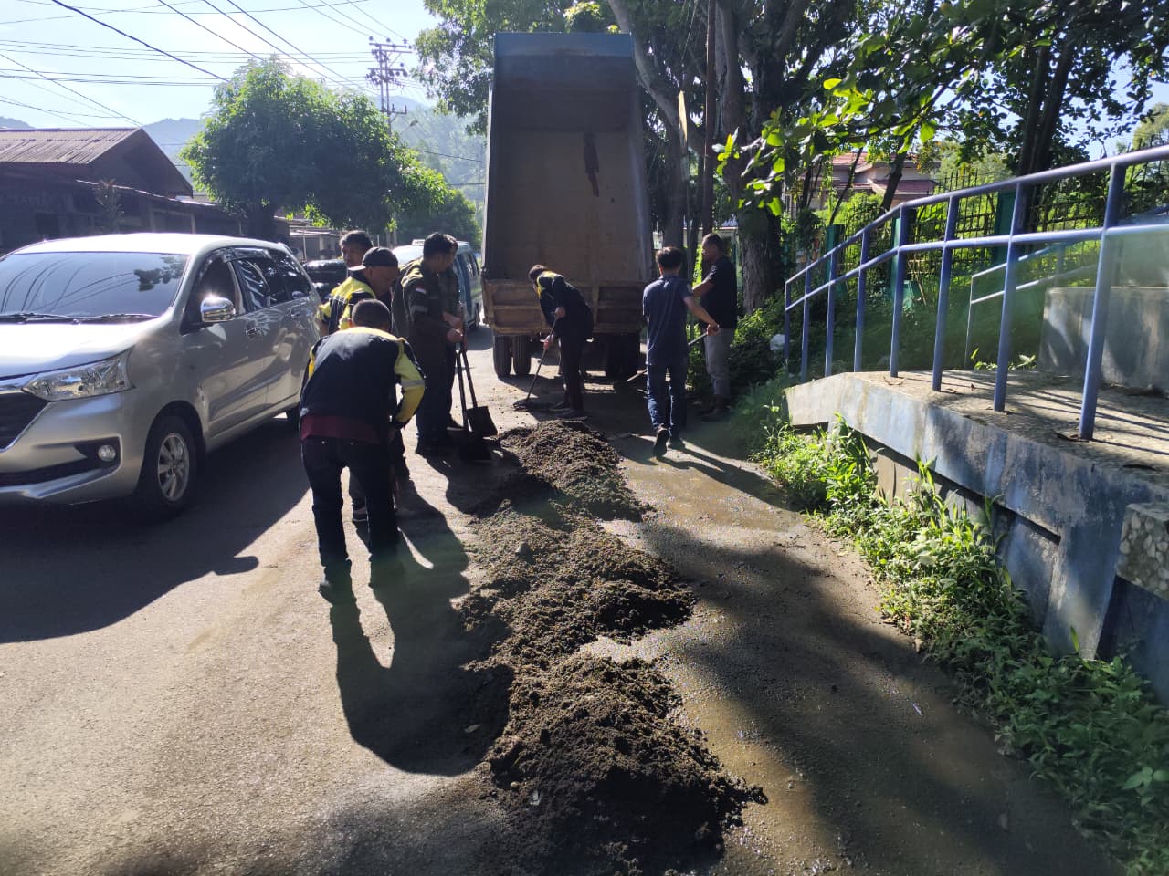 GERAK CEPAT: Sejumlah personel Bidang Bina Marga Dinas PUPR Kota Kotamobagu bergotong-royong membersihkan material endapan tanah dan sedimentasi di ruas Jalan Arief Rahman Hakim, tepatnya di kompleks GOR Ambang, Kotamobagu.