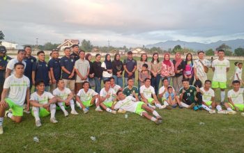 FOTO BERSAMA KEMENANGAN: Usai mencatatkan kemenangan telak 7-1 atas Bantong Sakti, tim sepak bola Amkey Kodim 1303/Bolmong (pemain berjersey putih-hijau neon) berfoto bersama jajaran ofisial, pendukung, dan Ketua Persit KCK Cabang XV, Ny. Irene Manashe Lomo (berdiri di tengah dengan jaket coklat). Kehadiran Ibu Ketua Persit dan suporter di pinggir lapangan menjadi motivasi tambahan bagi tim untuk menampilkan performa terbaik.