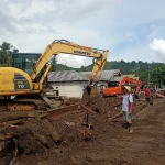 Sangadi Solimandungan Dua, Bebi Balongka, meninjau proses pembersihan material lumpur pascabanjir bandang di desanya bersama petugas gabungan menggunakan alat berat Komatsu PC70.