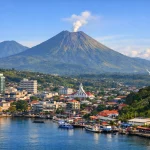 Harmoni di Nyiur Melambai: Pemandangan Kota Manado dengan latar Gunung Lokon yang ikonik. Keberhasilan Sulawesi Utara menembus 5 besar Indeks Kebahagiaan Nasional 2026 membuktikan bahwa keseimbangan antara pembangunan infrastruktur dan kualitas hidup masyarakat menjadi kunci kesuksesan di bawah kepemimpinan Gubernur Yulius Selvanus. (Foto: Dok. Istimewa)
