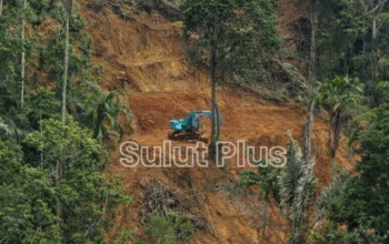 Salah satu unit excavator berwarna biru terlihat beroperasi di kawasan Hutan Produksi Osing-osing, Desa Mopait, Kecamatan Lolayan, Bolmong, meski aktivitas PETI ini menuai sorotan publik karena merusak lingkungan dan mengancam keselamatan warga.