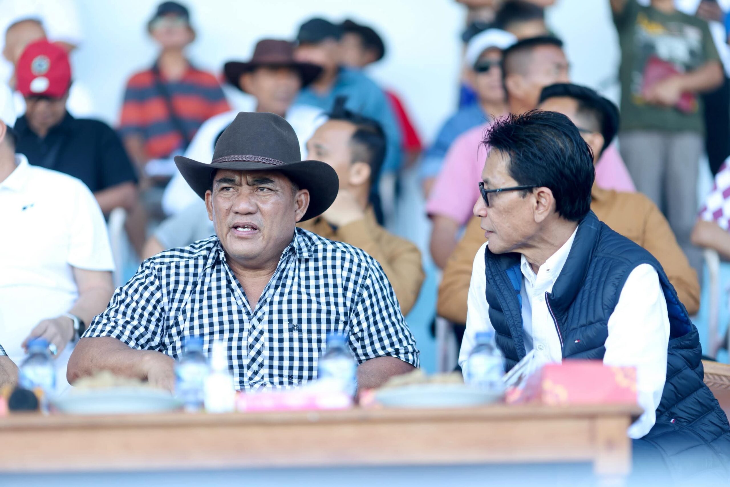 Gubernur Yulius Selvanus, mengenakan topi, tampak serius menonton jalannya Kejuaraan Pacuan Kuda Piala Gubernur 2026 di Tompaso, sembari menegaskan komitmen menjadikan Maesa Tompaso sebagai pusat olahraga berkuda nasional.