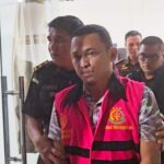 Eks Bendahara Pengeluaran KPU Boltim, Arga Karian, resmi mengenakan rompi tahanan Kejari Kotamobagu usai ditetapkan tersangka kasus korupsi dana rutin tahun 2021.