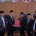 Bupati Iskandar Kamaru bersama Wakil Bupati Deddy Abdul Hamid menyerahkan dokumen Ranperda Pertanggungjawaban Pelaksanaan APBD 2025 kepada pimpinan DPRD Bolsel dalam Rapat Paripurna di Panango, Rabu (17/6/2026).