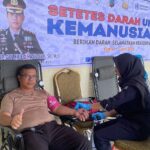 Kapolres Boltim AKBP Golfried Hasiholan Pakpahan mengacungkan jempol saat mendonorkan darahnya dalam acara peringatan Hari Bhayangkara ke-80. Kegiatan ini berlangsung di Aula Sanika Satyawada dengan latar belakang spanduk bertema "Setetes Darah untuk Kemanusiaan", Kamis (11/6/2026).