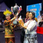Ibu Anik Wandriani menerima langsung Piala Presiden RI sebagai simbol kemenangan Juara Umum Pesparawi Nasional bagi kontingen Sulawesi Utara di Manokwari, Papua.