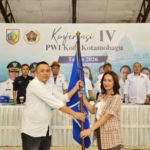 Ketua PWI Kotamobagu terpilih periode 2026–2029, Konni Balamba (kiri), menerima bendera organisasi dari perwakilan pengurus PWI Sulawesi Utara dalam Konferensi IV PWI Kota Kotamobagu di Gedung Kominfo, Jumat (26/6/2026).