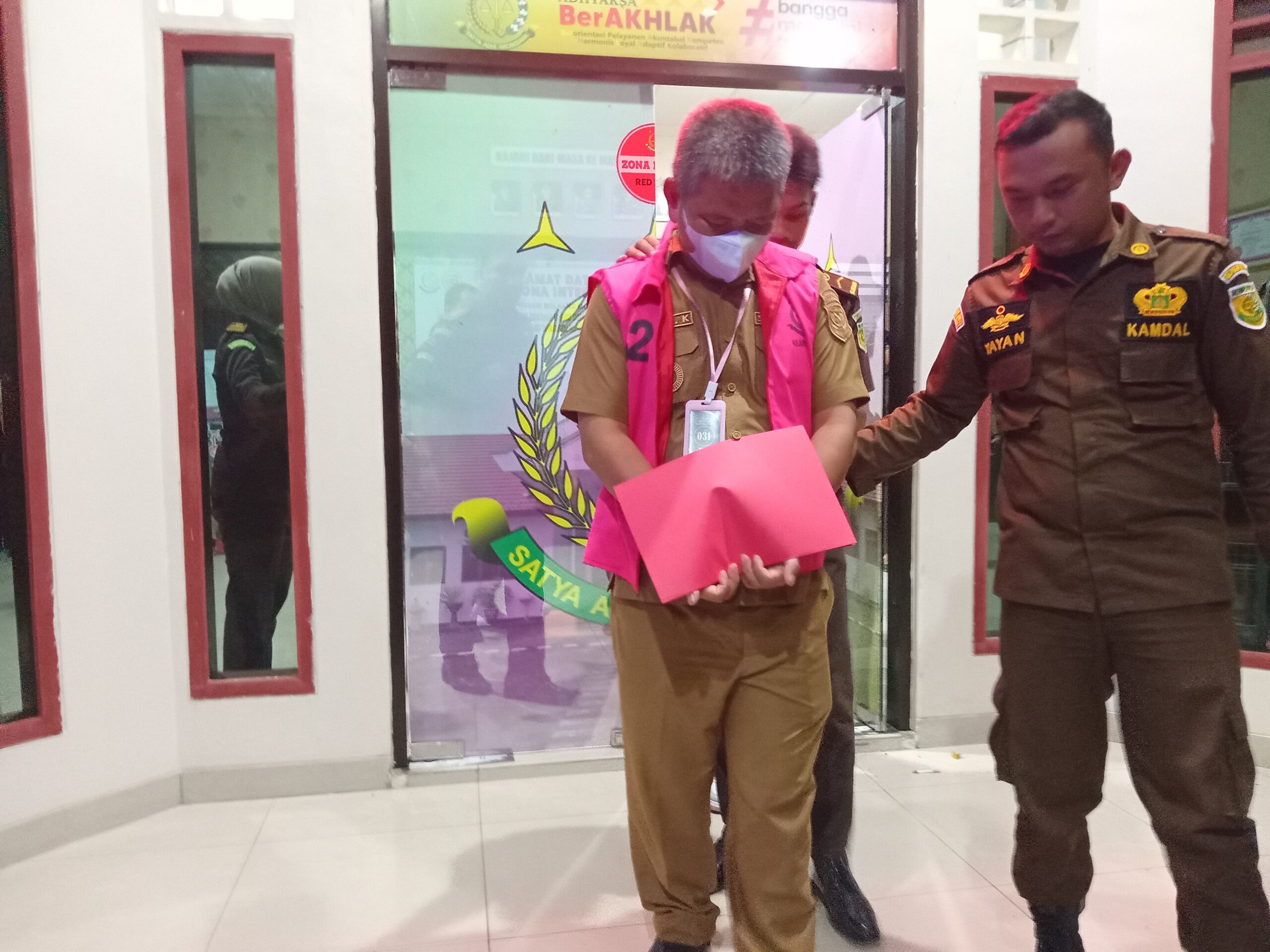 Petugas Kejaksaan Negeri Bolaang Mongondow Utara mengawal Kepala Desa Huntuk berinisial OFK bersama operator desa FU saat resmi ditahan terkait dugaan korupsi Dana Desa dan Alokasi Dana Desa Tahun Anggaran 2024 yang merugikan negara Rp442 juta. Foto: Wawan Golonda
